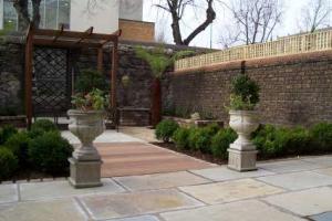 Ornamental urns and a hardwood path lead the eye into a garden of formal planting, flower beds, brick, stone and water. from project Townhouse Garden